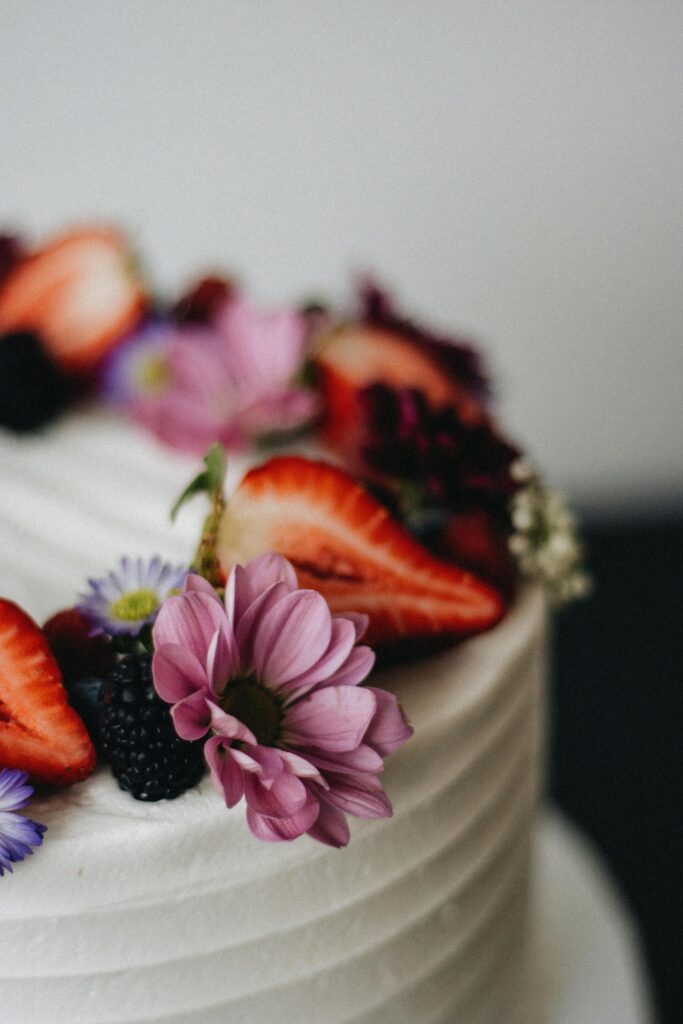 Close-up of a cake adorned with fresh berries and flowers, showcasing artisanal elegance.